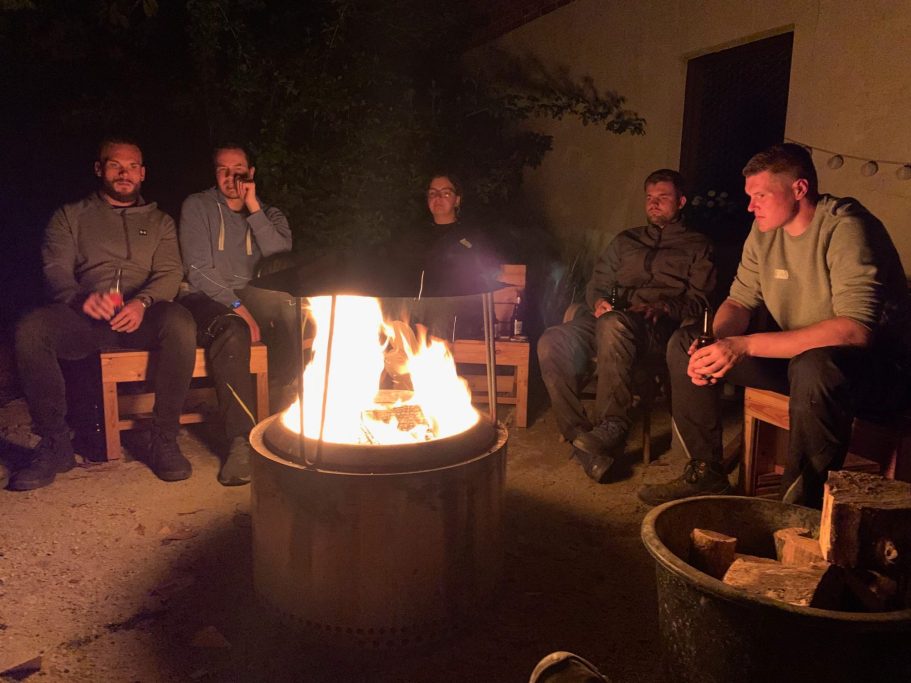 Entspannte Teamrunde am Lagerfeuer bei Sonnenuntergang